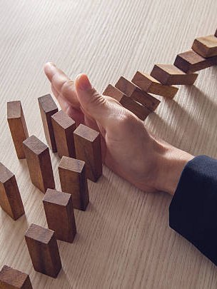 Businesswoman hand stopping the domino wooden effect concept for business.